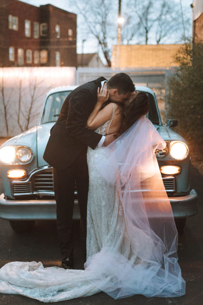 couple posing in a blue car for their wedding portraits