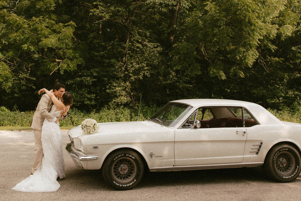 couple posing with a vintage car after their wedding day