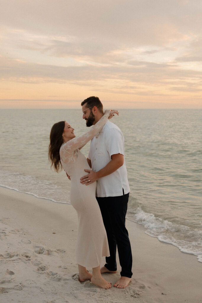 Happy couple at their baby announcement with Naples Beach as the backdrop