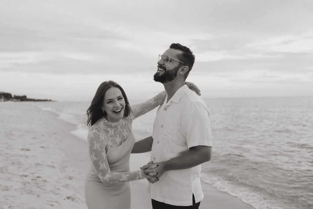 couple having fun during their baby announcement photoshoot with Naples beach as the backdrop