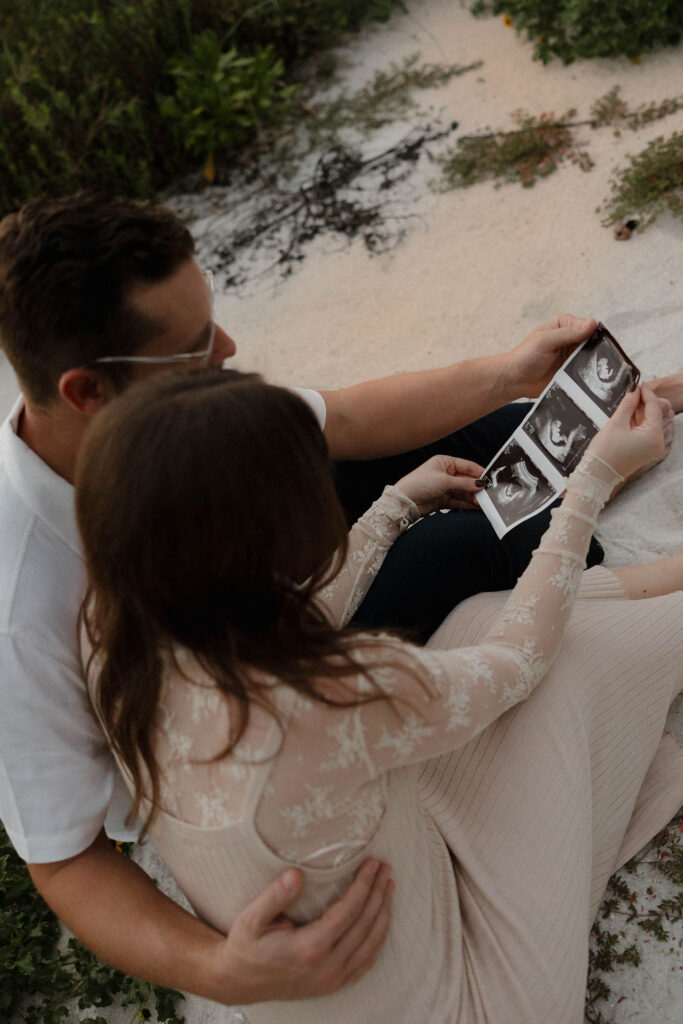 couple at Naples beach looking at their baby ultrasound
