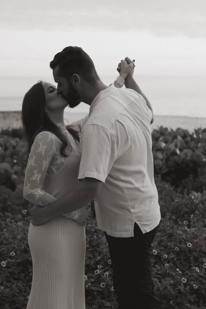 black and white photo of the couple kissing during their baby announcement 