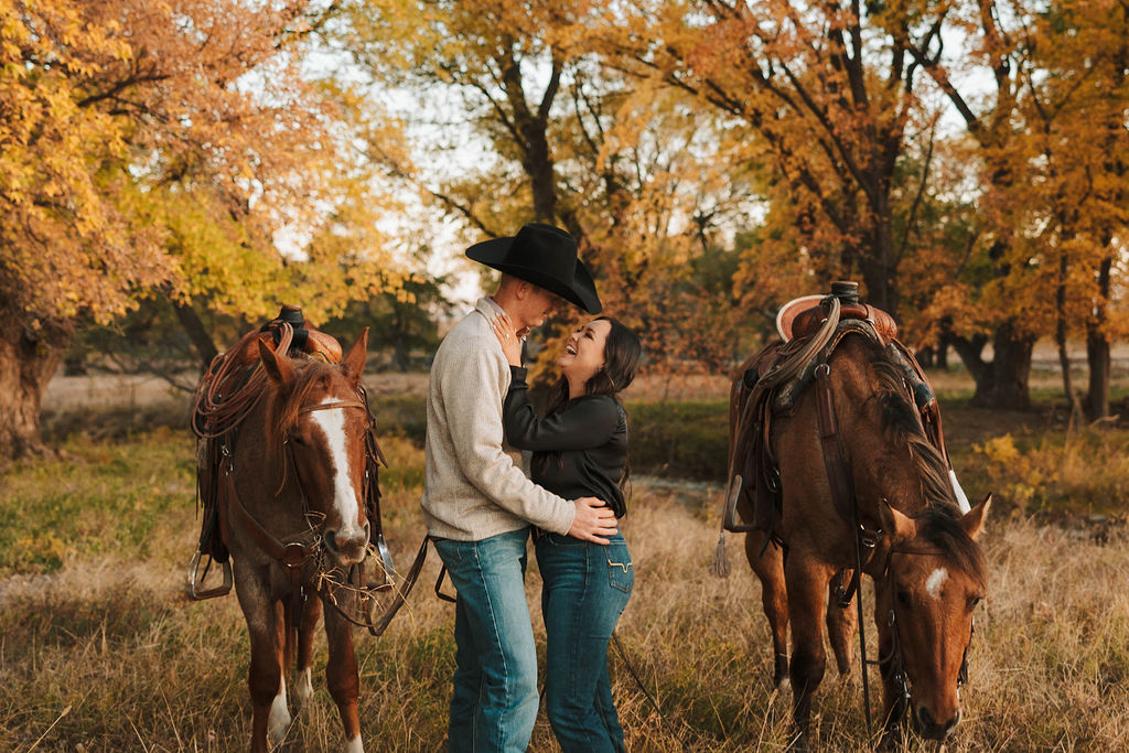 beautiful engaged couple during their engagement session with their horses in the background