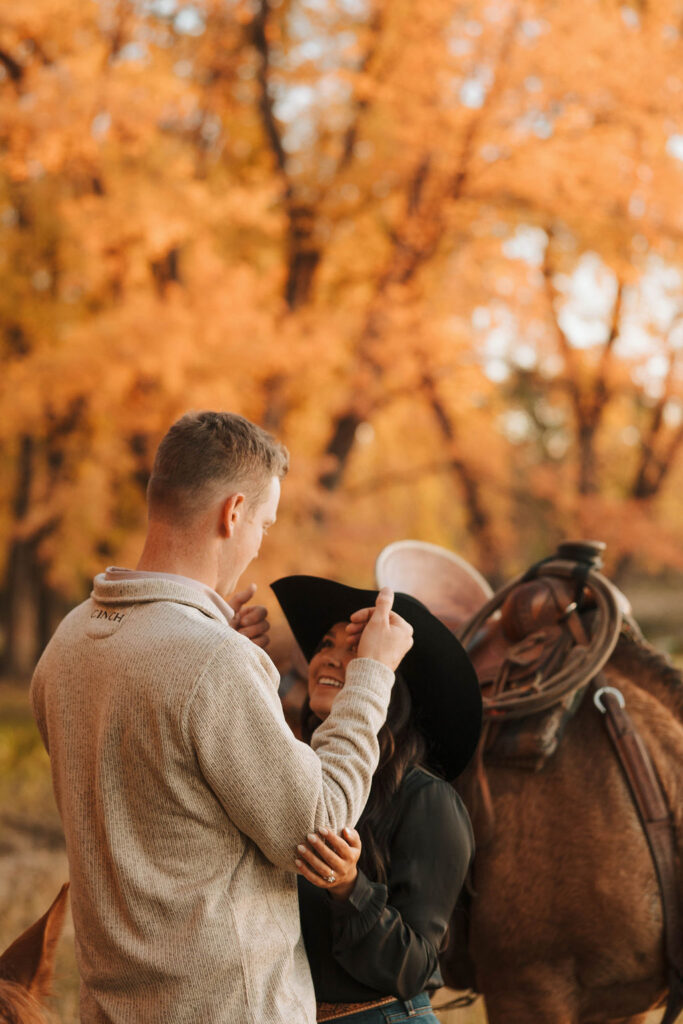 couple fixing their cowboy hats during their engagement photoshoot