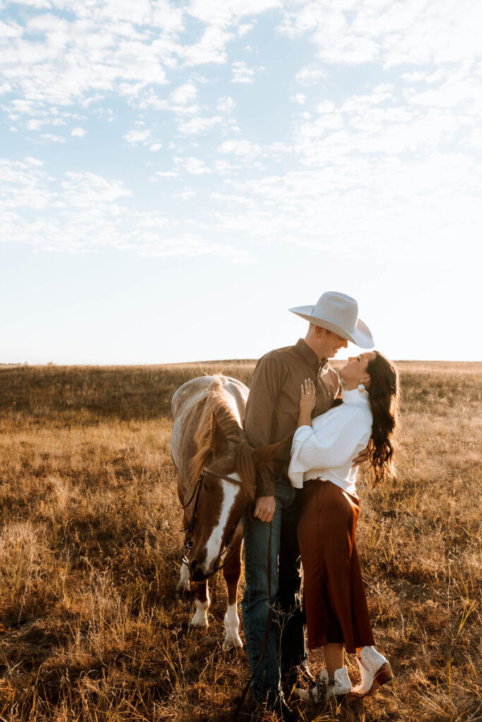 couple during their engagement session and their horse in the background 
